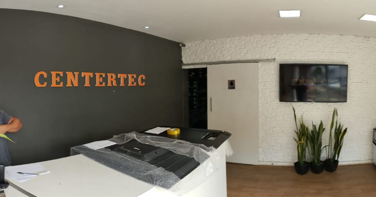 Interior da loja Centertec, com uma TV na bancada de atendimento
